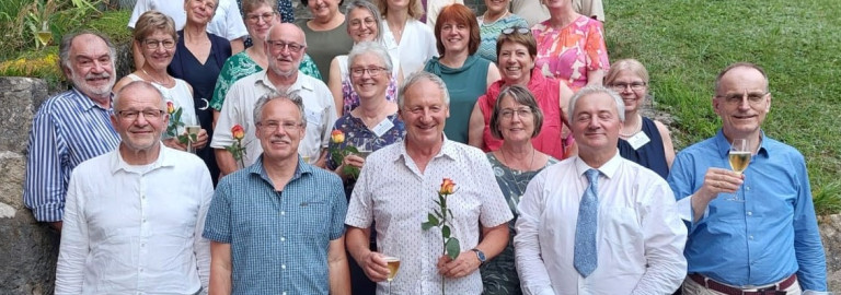 Gruppenbild mit Männer und  Frauen mit Rosen und Sektgläsern in der Hand