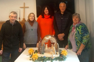 Menschen um eine Holzkrippe