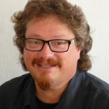 Mann mit Locken, Spitzbart und schwwarzer Brille