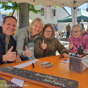 Familie malt Bild am Biertisch und zeigt Daumen hoch Finger