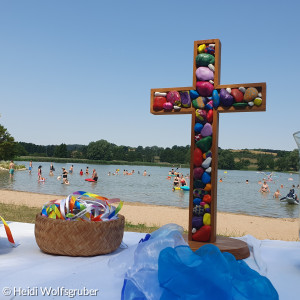 Buntes Kreuz auf Altar vor See